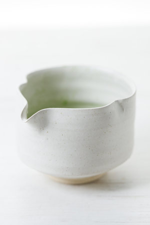 Cup of fresh matcha tea, green tea on white wooden table. Selective focus.の写真素材