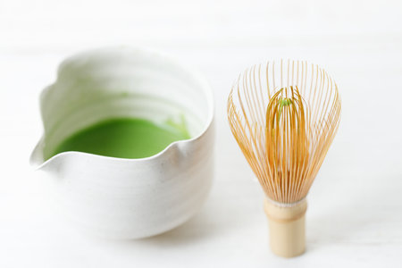 Cup of fresh matcha tea, green tea and Chasen, bamboo whisk, on white wooden table. Selective focus.の写真素材