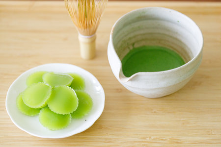 Cup of fresh matcha tea, green tea and Steamed Pandan Layer Cake, Thailand dessert on wooden table. Selective focus.の写真素材