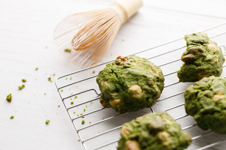 Closeup of fresh baked matcha cookies with Chasen, bamboo whisk, on white wooden background. Selective focus.の写真素材