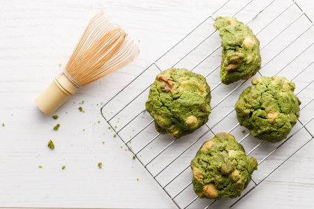 Closeup of fresh baked matcha cookies with Chasen, bamboo whisk, on white wooden background. Selective focus.の写真素材