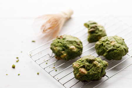 Closeup of fresh baked matcha cookies with Chasen, bamboo whisk, on white wooden background. Selective focus.の写真素材