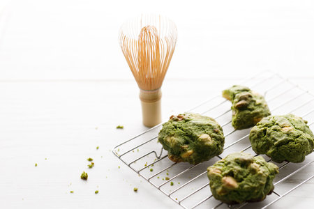 Closeup of fresh baked matcha cookies with Chasen, bamboo whisk, on white wooden background. Selective focus.の写真素材