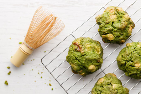 Closeup of fresh baked matcha cookies with Chasen, bamboo whisk, on white wooden background. Selective focus.の写真素材