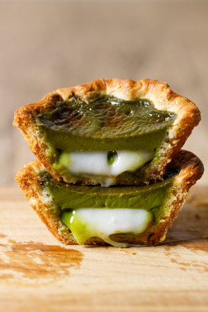Closeup of Matcha and mochi Portuguese sweet dessert egg tart or Pastel de Nata on wooden board on...