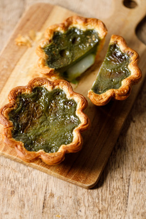 Closeup of Matcha and mochi Portuguese sweet dessert egg tart or Pastel de Nata on wooden board on wooden table.  Selective focus.の写真素材