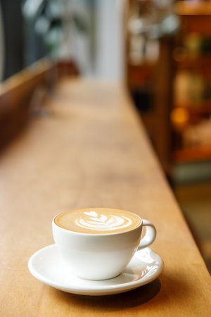 Cup of hot milk latte coffee on table by the window. Selective focus.の写真素材