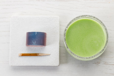 Cup of fresh matcha tea, green tea and Kingyoku can, traditional Japanese jelly confectionery on white wooden table. Selective focus.の写真素材
