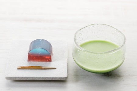 Cup of fresh matcha tea, green tea and Kingyoku can, traditional Japanese jelly confectionery on white wooden table. Selective focus.の写真素材