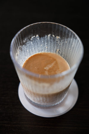 Glass of delicious cold milk chocolate on black wooden table background. Selective focus.