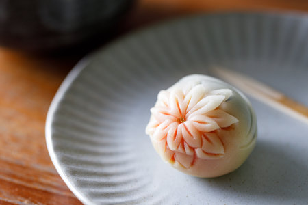 A piece of delicious Japanese confectionery on off white ceramic plate on wooden table. Selective focus.の写真素材