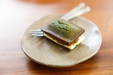 A piece of Cheese and Matcha and red bean paste financier, small almond cake, on wooden table....
