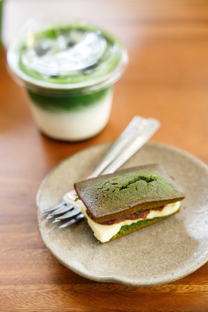 Cup of fresh matcha tea, green tea and  financier, small French almond cake, on wooden table. Selective focus.の写真素材