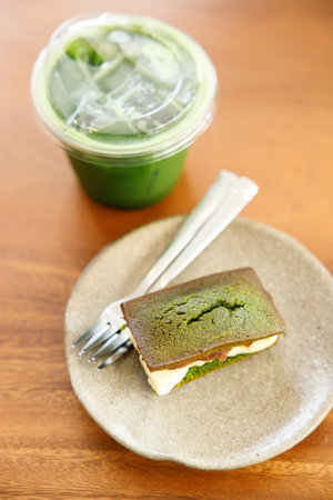 Cup of fresh matcha tea, green tea and financier, small French almond cake, on wooden table. Selective focus.の写真素材