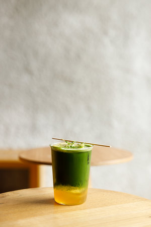 Creation beverage of fresh matcha tea, green tea and lemon juice on wooden table by the window. Selective focus.の写真素材