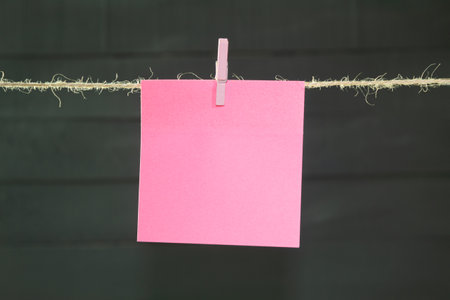 The paper for the text is suspended from a rope. Photo frames hanging on a rope, note paper on clothespins. Background with copy spaceの写真素材