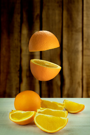 Fresh orange hovered in the air on a light wooden background. Levitation of orange on wood background with space for textの写真素材