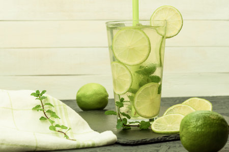 Fresh and chilled citrus drink on a wooden table. Homemade refreshing iced tea with orange and...