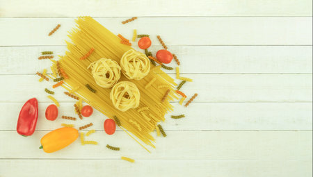 Raw pasta of various types and spices on a wooden table. View from above. Macaron on wooden table, space for textの写真素材