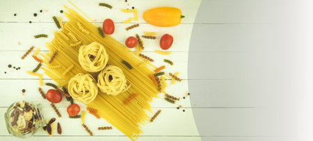 Raw pasta of various types and spices on a wooden table. View from above. Macaron on wooden table, space for textの写真素材
