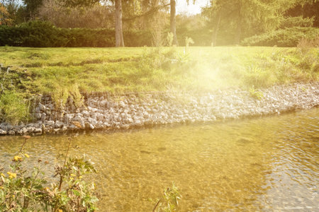 Strengthening the banks of the river, mesh and stones. Landscape river bank and large stones with metal mesh. solar glareの写真素材