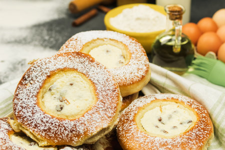 Fresh pastries on the background of ingredients for baking. Freshly baked buns on a wooden table. Background of baking, confectionery. Free space for textの写真素材