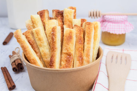 Delicious and sweet puff pastry sticks with cinnamon. Background with copy space