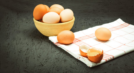 Fresh chicken eggs in a bowl, close-up. Raw chicken white eggs on dark background with space for...