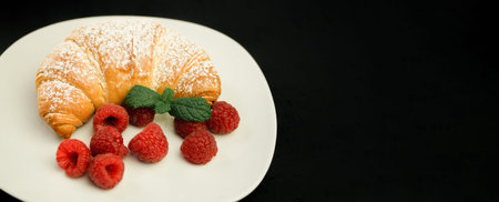 Appetizing crispy croissant and fresh raspberries on a white plate. French breakfast. Fresh fragrant...