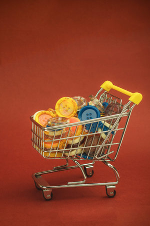 Multi-colored buttons of different shapes in a shopping cart. Lots of colorful buttons for clothes of different sizes. Side viewの写真素材
