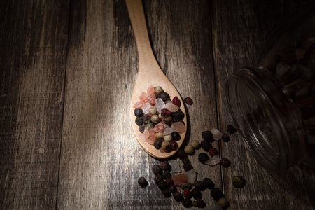 Spices and salt in a spoon on a dark wooden background. On the table are spices for cooking. copy...