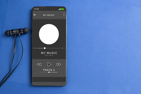 Wired headphones and a phone on the table. Mobile phone and headphones, music is playing on the player. Close-up. Player on screen, copy spaceの写真素材