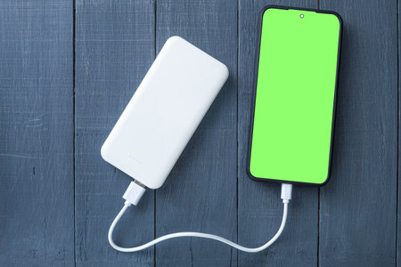 Phone with chroma key screen, wooden background. Copy space. Photo of a mobile phone with a green...