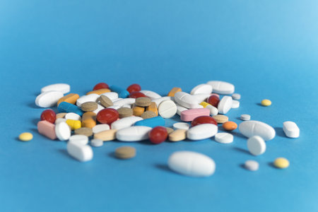 Many pills, different shapes and different colors on a blue background. Medical and pharmaceutical treatment concepts. Copy spaceの写真素材