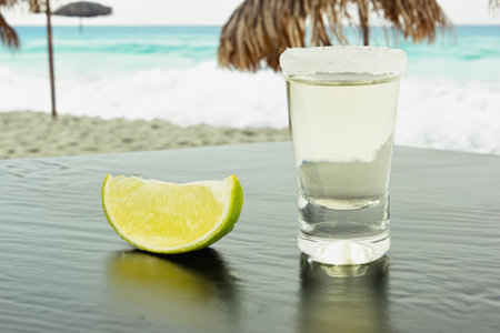 A shot of tequila with salt and lime. Tequila on the background of a Mexican beach. Golden Mexican Tequila. Copy spaceの写真素材