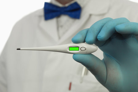 Electronic thermometer in the hands of a doctor, close-up. Chromakey. Copy space. Doctor in medical glovesの写真素材