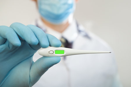 Electronic thermometer in the hands of a doctor, close-up. Chromakey. Copy space. Doctor in medical glovesの写真素材