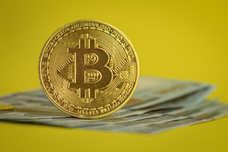 Bitcoin gold coin close up. Bitcoin cryptocurrency on US 100 dollar bills. Bitcoin coins and cash. Background with copy spaceの写真素材