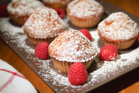 Fresh cupcake sprinkled with powdered sugar. Homemade cupcakes with raspberries. Photo of fresh baked goods, background with copy spaceの写真素材