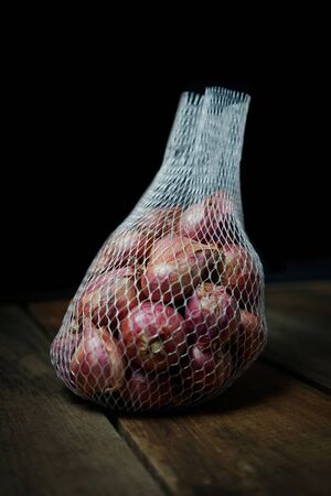 red garlic in net basket with black background.の写真素材
