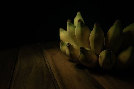 banana on wooden table in black background.の写真素材