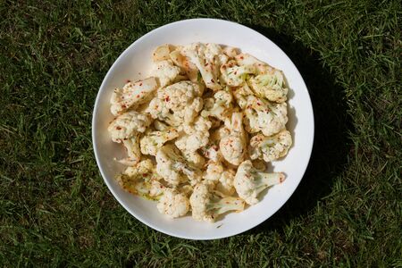 A dish of raw cauliflower sprinkled with chilli and herbsの写真素材