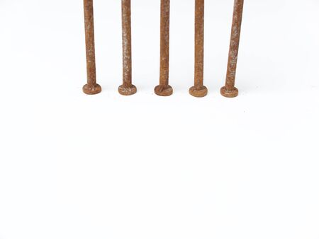 Five very rusty metal nail heads against a white backgroundの写真素材