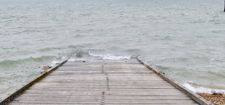 Slipway leading down beach into grey sea with copy spaceの写真素材