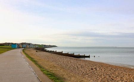 Stony beach with breakwater and beach huts in the distanceの写真素材