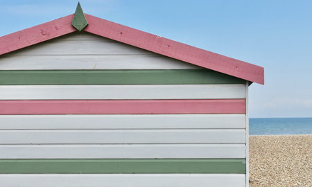 Painted wooden beach hut in white pink and green with sea to side