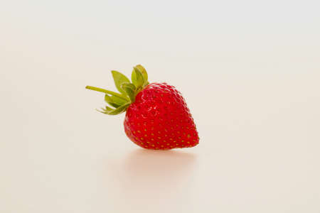 Single strawberry against plain white background with space for copyの写真素材