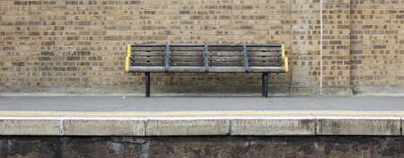 Public seating on station platform with old weathered brick wall behindの写真素材