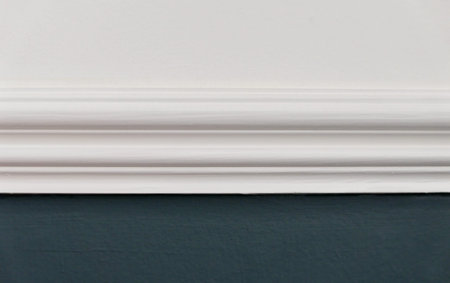 Close up of white dado rail with white above and teal blue green below