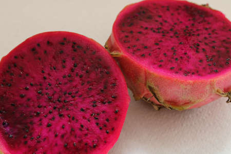Pithaya cut in half showing dark pink interior and black seedsの写真素材